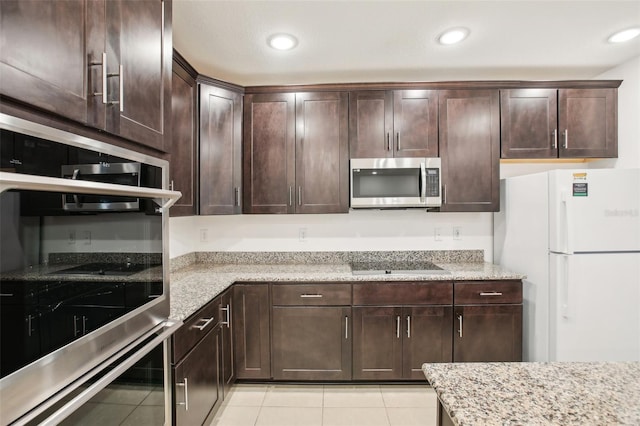 kitchen with light stone counters, light tile patterned floors, appliances with stainless steel finishes, and dark brown cabinetry