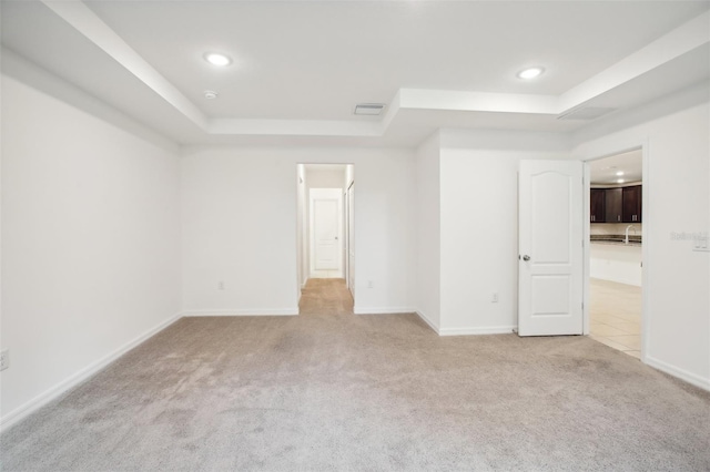 unfurnished bedroom featuring light carpet and a tray ceiling