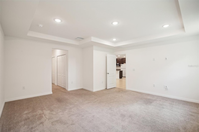 empty room with a tray ceiling and light carpet