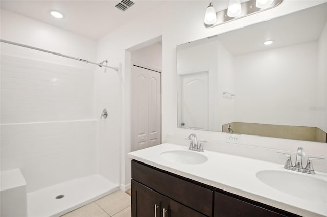 bathroom with tile patterned flooring, walk in shower, and vanity