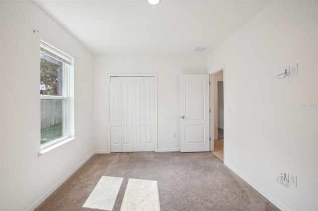 unfurnished bedroom featuring a closet, multiple windows, and light colored carpet