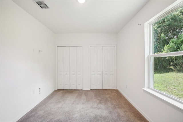 unfurnished bedroom with carpet and multiple closets