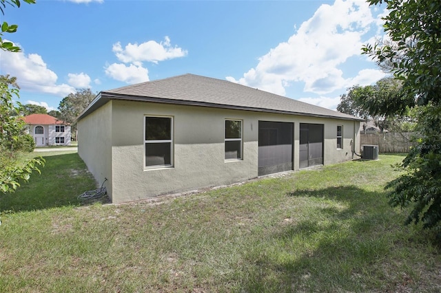 rear view of property featuring a yard and central air condition unit