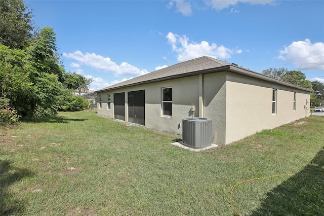 rear view of property featuring cooling unit and a yard