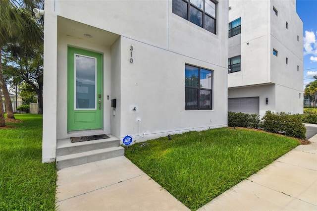 property entrance featuring a garage and a lawn