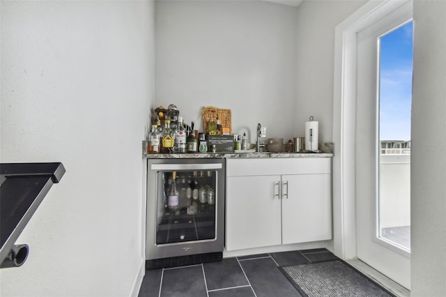 bar featuring dark tile patterned flooring, white cabinetry, beverage cooler, and sink