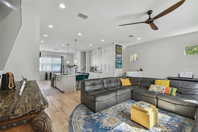 living room featuring light hardwood / wood-style flooring, ceiling fan, and sink