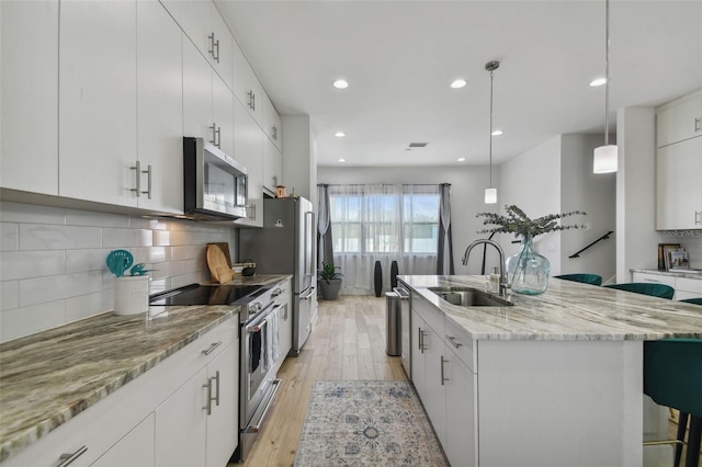 kitchen with white cabinets, sink, stainless steel appliances, and hanging light fixtures