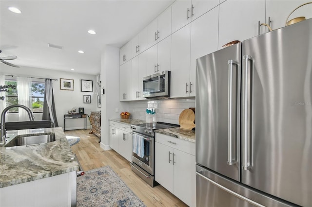 kitchen with white cabinetry, sink, light stone counters, and appliances with stainless steel finishes