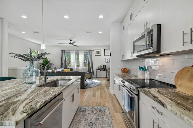 kitchen featuring white cabinetry, sink, hanging light fixtures, stainless steel appliances, and light hardwood / wood-style flooring