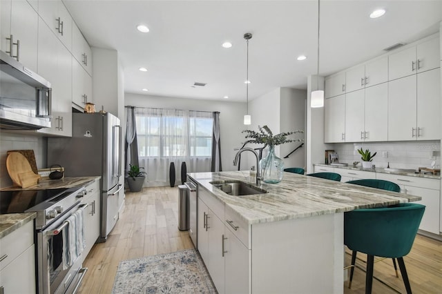 kitchen featuring a center island with sink, sink, white cabinetry, and stainless steel appliances