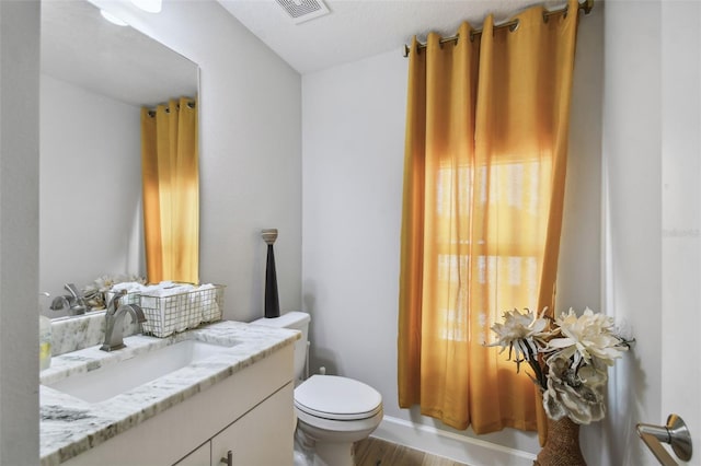 bathroom with hardwood / wood-style floors, vanity, and toilet