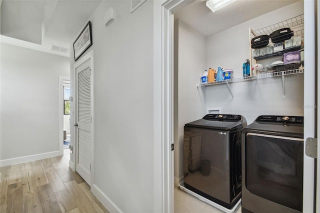 laundry room featuring separate washer and dryer and light hardwood / wood-style floors