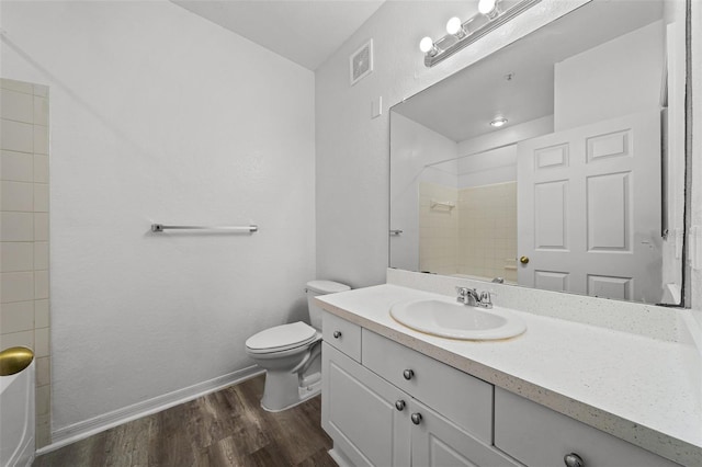 bathroom with vanity, toilet, wood-type flooring, and tiled shower