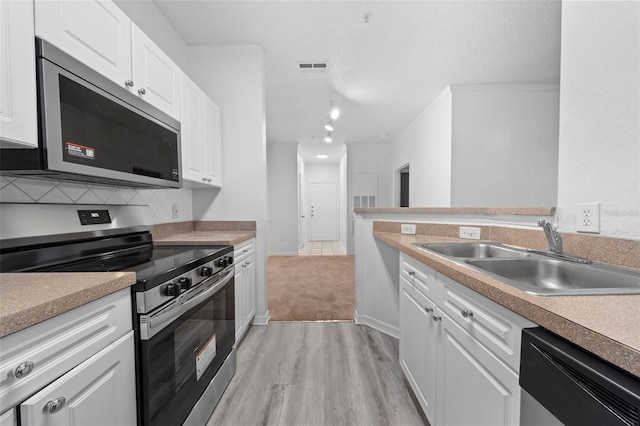 kitchen with sink, white cabinets, light hardwood / wood-style flooring, and appliances with stainless steel finishes