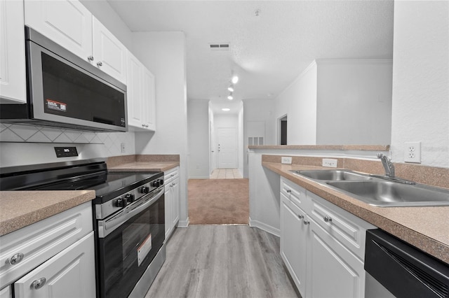 18001 Richmond Place Dr Unit 511, Tampa, FL 33647 - kitchen with stainless steel appliances, a sink, white cabinetry, light wood finished floors, and decorative backsplash