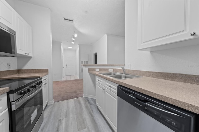 kitchen with white cabinetry, sink, light hardwood / wood-style floors, a textured ceiling, and appliances with stainless steel finishes