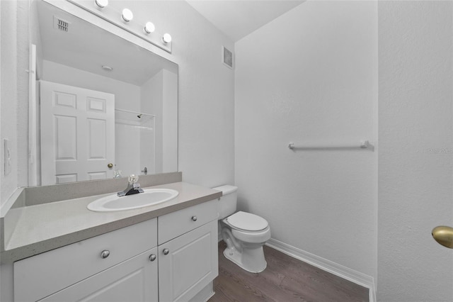 bathroom featuring hardwood / wood-style flooring, vanity, toilet, and walk in shower