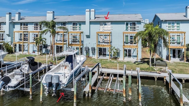 view of dock with a balcony, a yard, and a water view