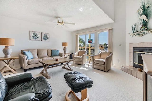 carpeted living room with ceiling fan, a textured ceiling, and a tile fireplace