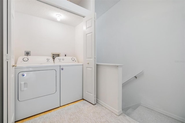 laundry room featuring washing machine and dryer, a textured ceiling, and light colored carpet