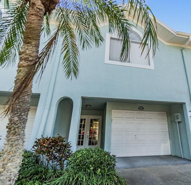 view of front of home with a garage, concrete driveway, and stucco siding