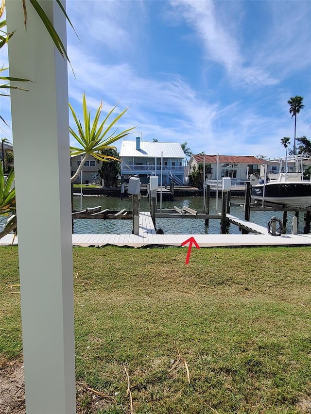 view of dock featuring a water view, boat lift, and a lawn