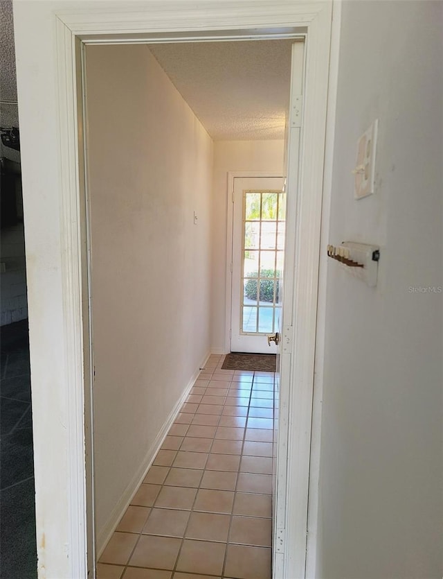 doorway to outside with baseboards and light tile patterned floors