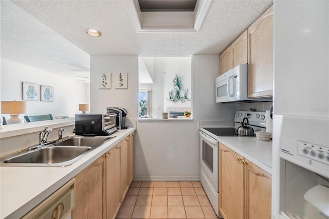 kitchen featuring white appliances, light countertops, a sink, and light brown cabinetry