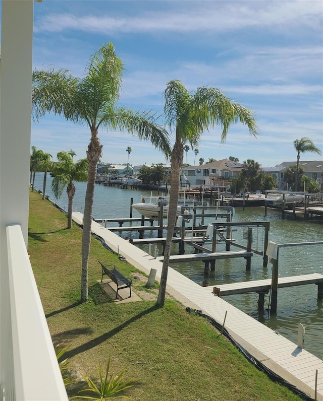 view of dock featuring a water view, boat lift, and a lawn