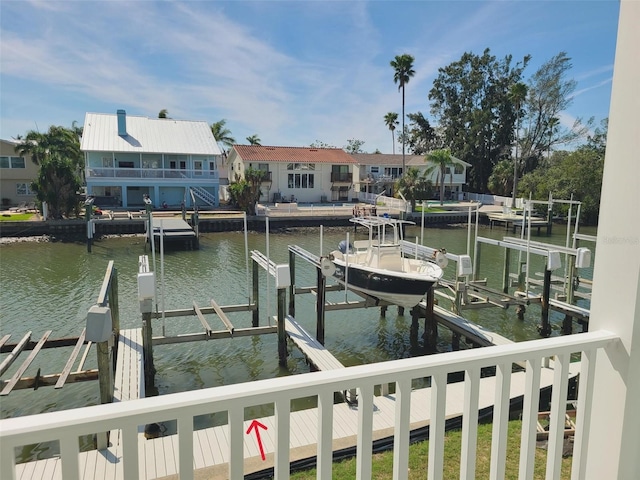 dock area with a water view, boat lift, and a residential view