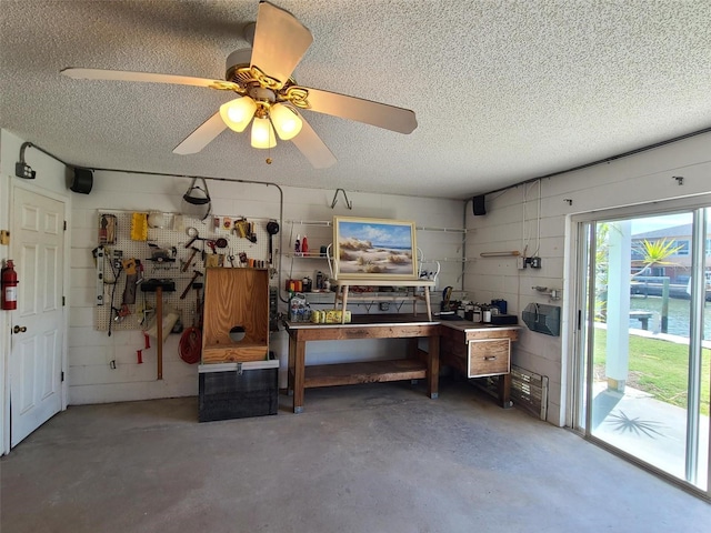 interior space featuring a textured ceiling, a ceiling fan, concrete flooring, and a workshop area