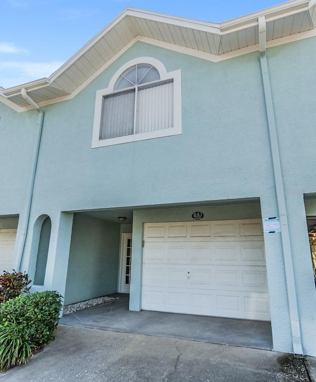 view of property with concrete driveway, an attached garage, and stucco siding