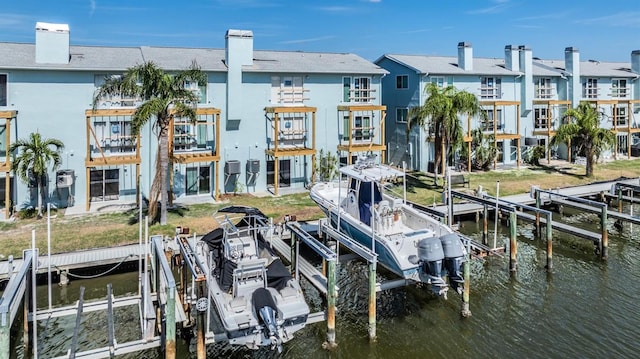 dock area with a water view, boat lift, and a residential view