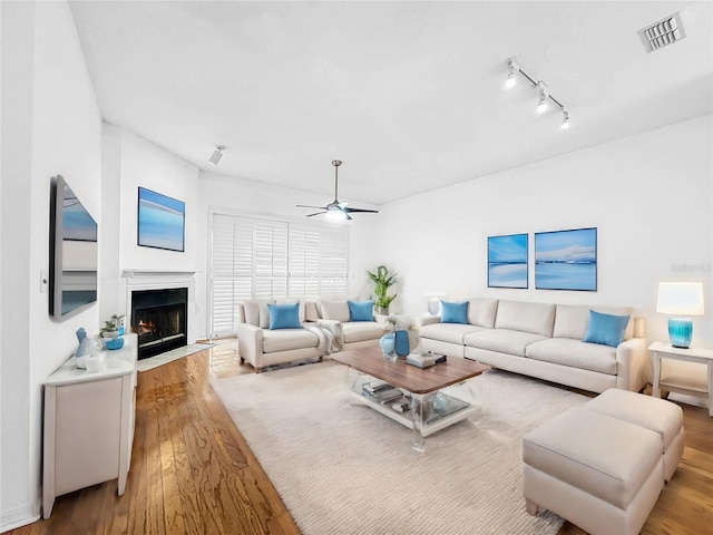 living room with wood-type flooring, ceiling fan, and a high end fireplace