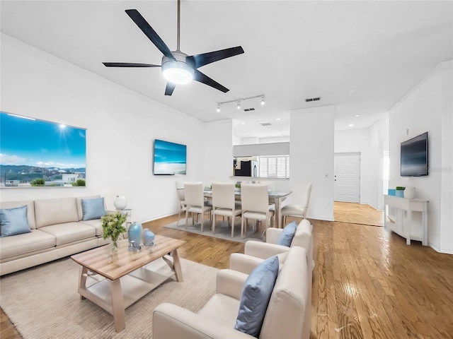 living room with light hardwood / wood-style floors, ceiling fan, and track lighting