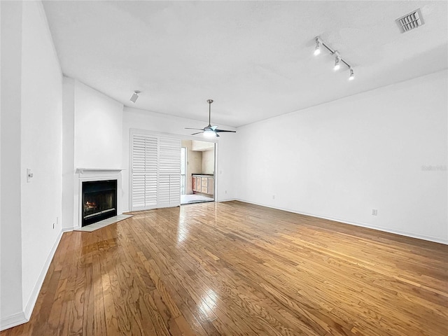 unfurnished living room with ceiling fan, track lighting, and wood-type flooring