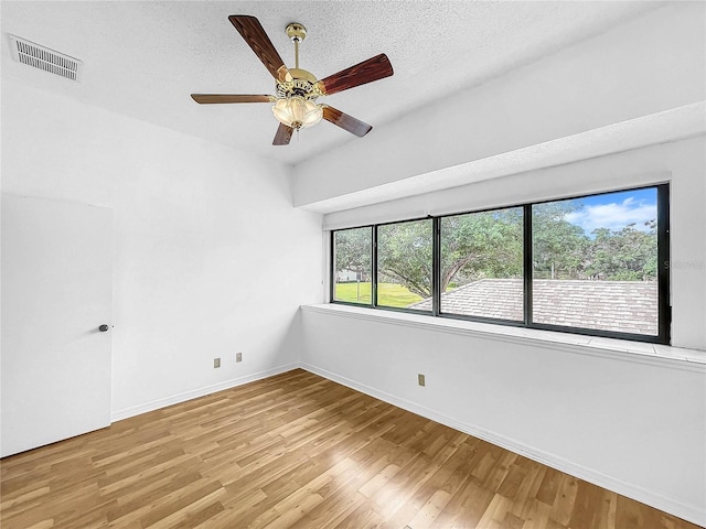 empty room featuring light wood-type flooring, a textured ceiling, and ceiling fan