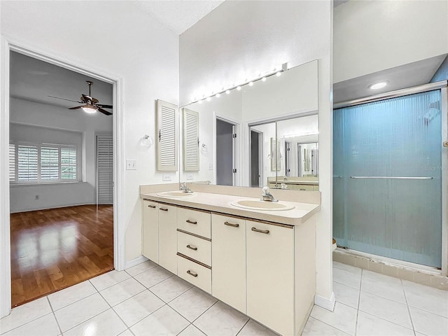 bathroom with ceiling fan, vanity, a shower with shower door, and tile patterned floors