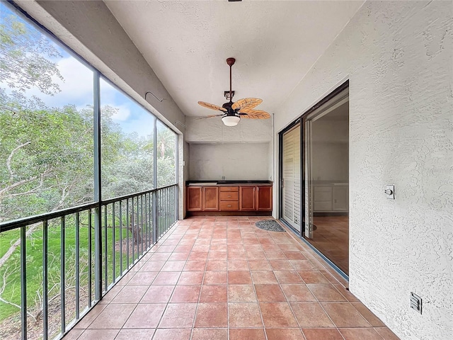 unfurnished sunroom with ceiling fan