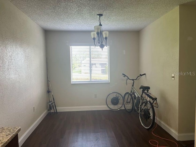 miscellaneous room with a textured ceiling, a chandelier, and dark hardwood / wood-style flooring