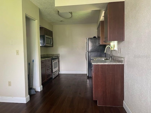 kitchen with a textured ceiling, appliances with stainless steel finishes, sink, and dark hardwood / wood-style flooring