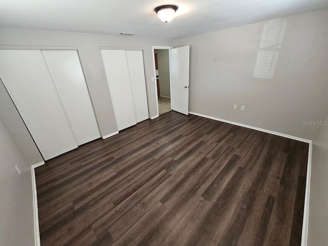 unfurnished bedroom featuring two closets and dark hardwood / wood-style flooring