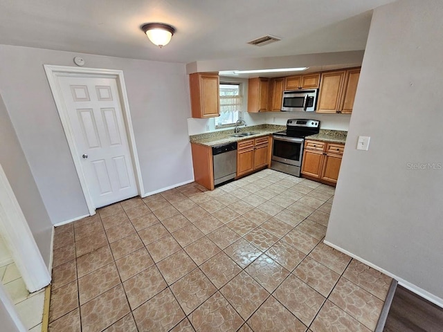 kitchen featuring light tile patterned flooring, stainless steel appliances, sink, and light stone counters