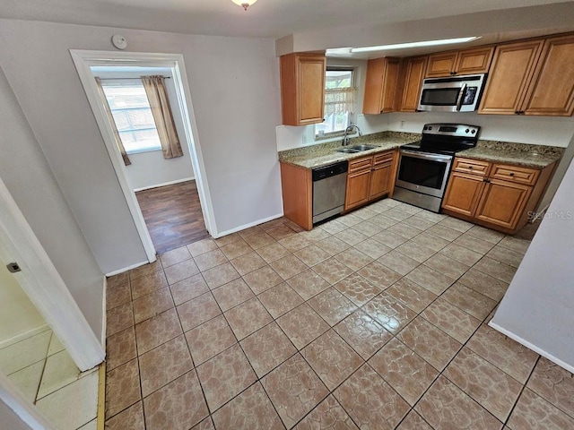 kitchen featuring sink, light tile patterned floors, appliances with stainless steel finishes, and a wealth of natural light