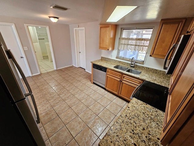 kitchen with sink, black range oven, stainless steel dishwasher, light stone counters, and light tile patterned floors