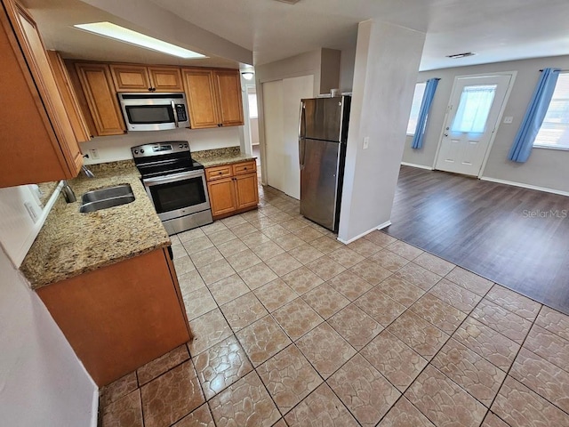 kitchen featuring light stone counters, appliances with stainless steel finishes, sink, and light wood-type flooring