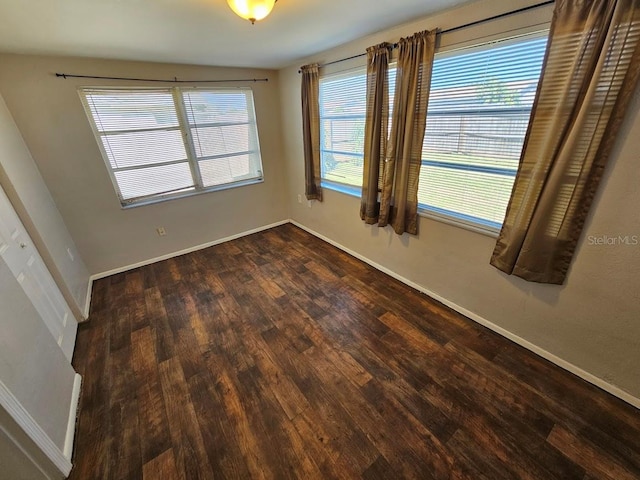 empty room with a healthy amount of sunlight and dark hardwood / wood-style flooring