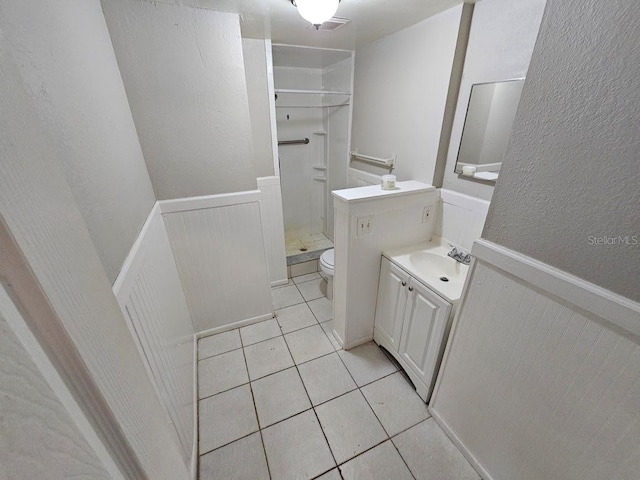 bathroom featuring vanity, a shower, toilet, and tile patterned flooring