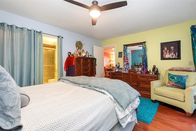 bedroom with ceiling fan, a textured ceiling, connected bathroom, and hardwood / wood-style floors